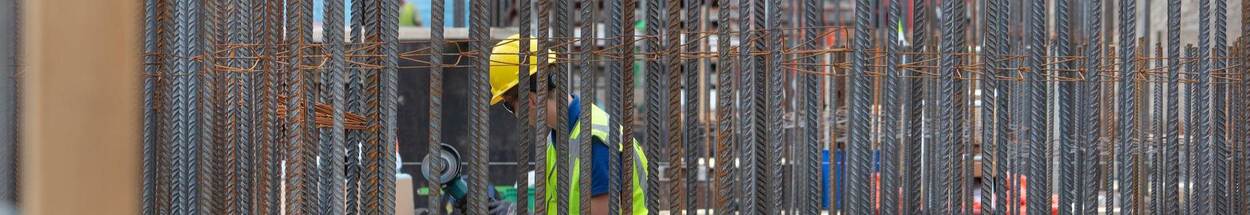 Bouwvakker temidden van een stalen constructie en rood-witte rand welke associeert met een gevangenis