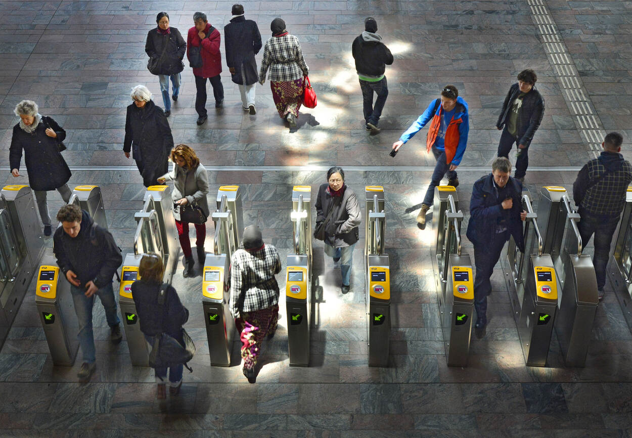 Diverse ov-reizigers passeren poortjes op een station - bovenaanzicht