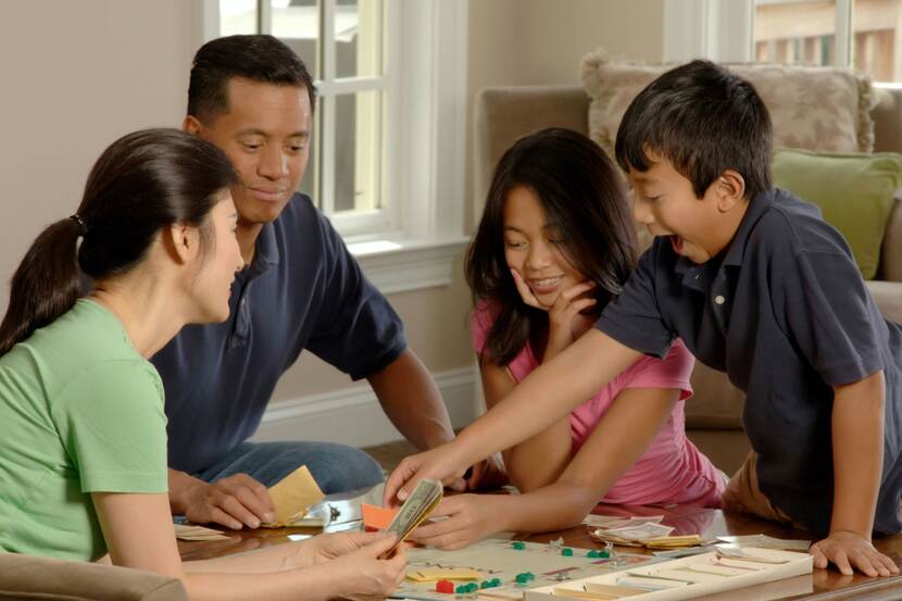 Gezin van Aziatische afkomst speelt een bordspel in een woonkamer