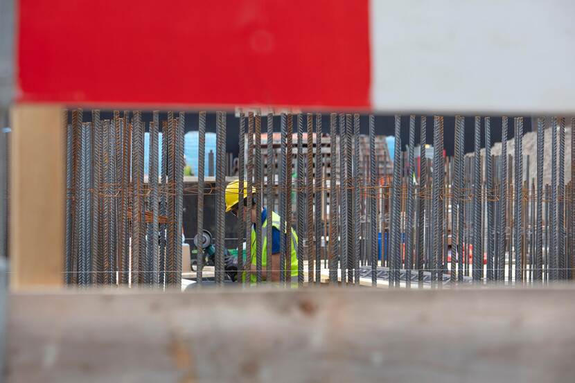 Bouwvakker temidden van een stalen constructie en rood-witte rand welke associeert met een gevangenis