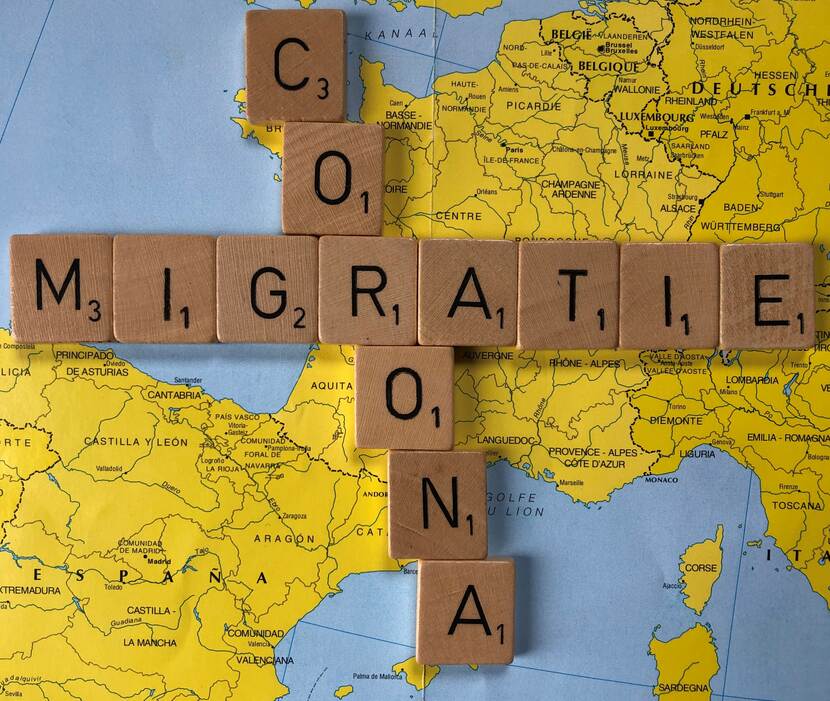 Scrabblewoorden corona en migratie op landkaart